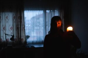 woman-holds-candle-in-dark-home